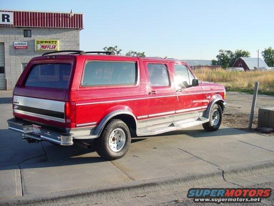Red SUV with silver trim parked outside a building. It has a sunroof and chrome running boards