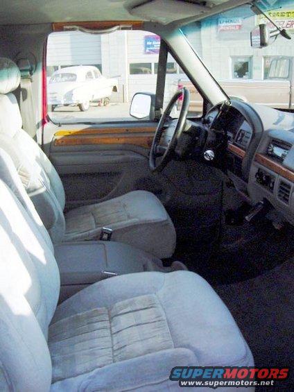 1994 Ford C-150 (Centurion Conversions) interior showing front seats, dashboard, and steering wheel. A white classic car is visible through the side window