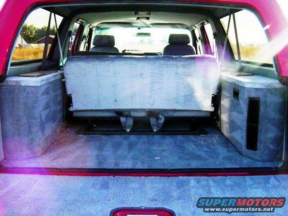 Interior view of a red SUV with gray upholstered rear bench seat and custom side panels