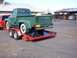 1954 Ford F-250 - A green 1953 Ford F-250 pickup truck is seen from the rear, loaded onto a red trailer.