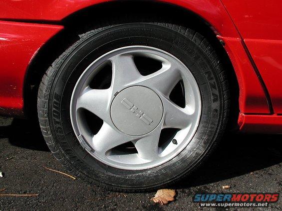 Red car's silver five-spoke wheel with a 'GMC' logo on the hubcap, showing a Bridgestone tire