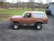 1991 Ford Bronco - This lifted 1992 Ford Bronco has a two-tone brown and tan exterior and is shown from the side.