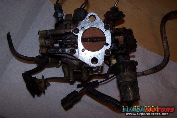 Carburetor with metal and rubber hoses, electrical connectors, and a date stamp of 11/05/2004