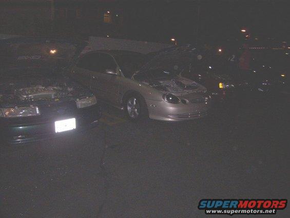Silver sedan with hood open, front quarter view, dark conditions