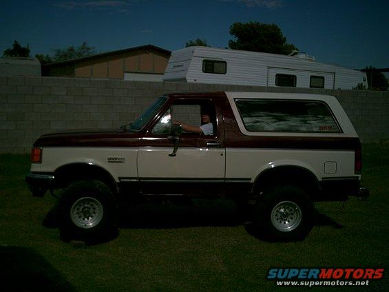 Two-tone maroon and white Ford Bronco parked on grass