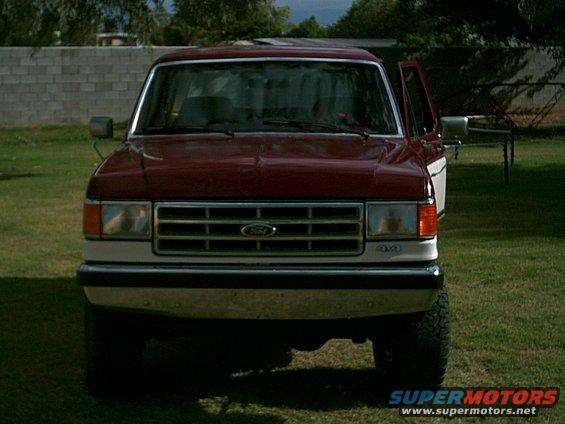 Red and white Ford truck front view. Grille indicates 1987 model