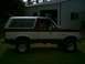 1988 Ford Bronco - Side view of a two-tone maroon and white 1988 Ford Bronco parked on grass.