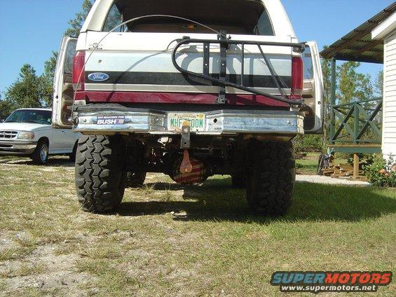Rear view of lifted 1993 Ford Bronco with large tires, spare tire carrier, and Florida license plate. Another SUV is parked to the left