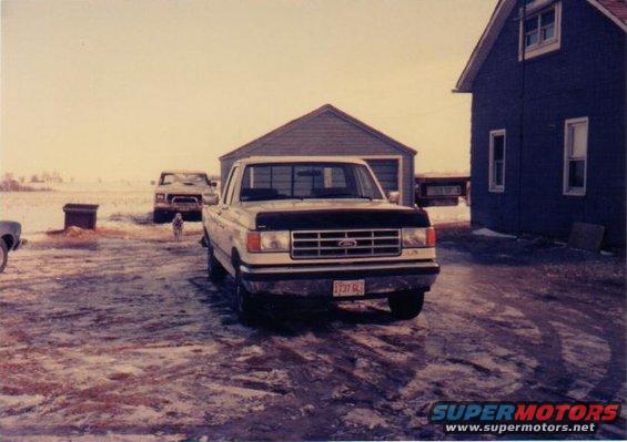 1987 Ford F-150 pickup truck parked in front of a garage with another truck in the background