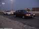2000 Ford Crown Victoria - Two Ford Crown Victorias, one maroon and one white, travel down a highway as twilight descends.
