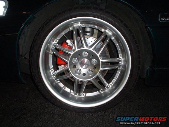 Close-up of a shiny multi-spoke alloy wheel with a red brake caliper visible behind it