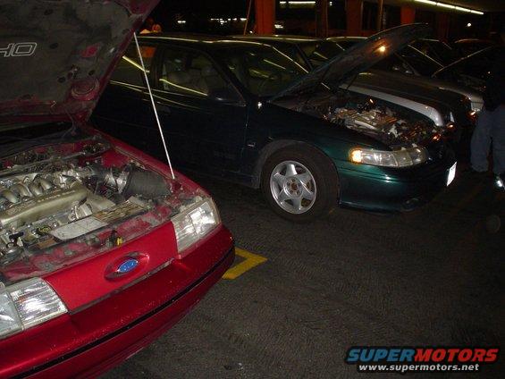 Red car front end and green 1998 Mercury Sable side view, both with hoods open