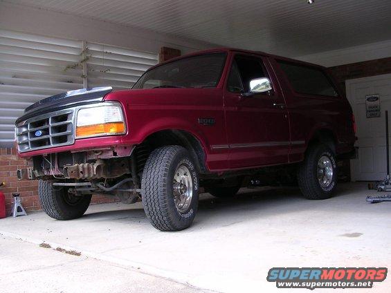 Red Ford Bronco parked in garage, front bumper removed