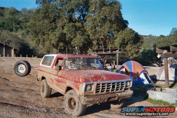 Red 1978 Ford Bronco with spare tire on trailer, parked at campsite