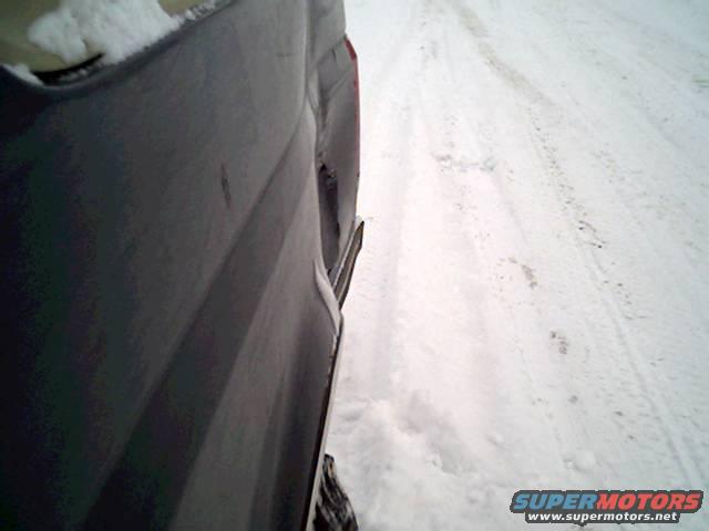 Dark SUV rear quarter panel with snow on the ground