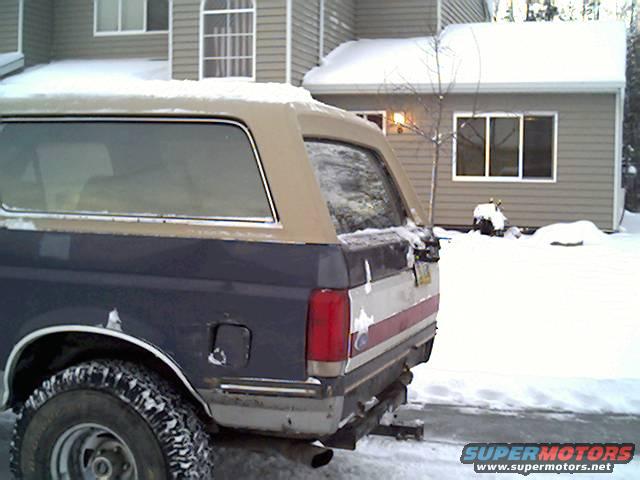 Rear of a blue and tan 1987 Ford Bronco parked in the snow