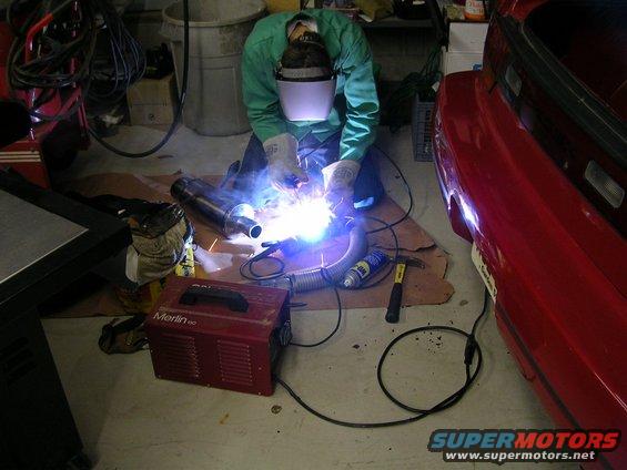 Red car rear end with exhaust pipe being welded