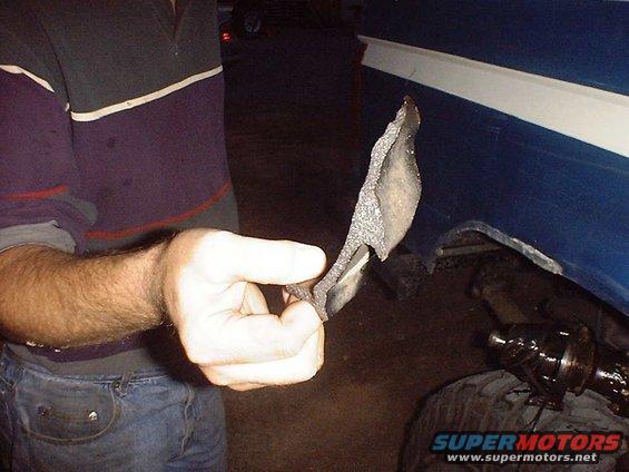 Hand holding a torn piece of blue vehicle trim with white stripe
