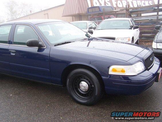 Dark blue 2001 Ford Crown Victoria sedan with black steel wheels, parked on wet asphalt