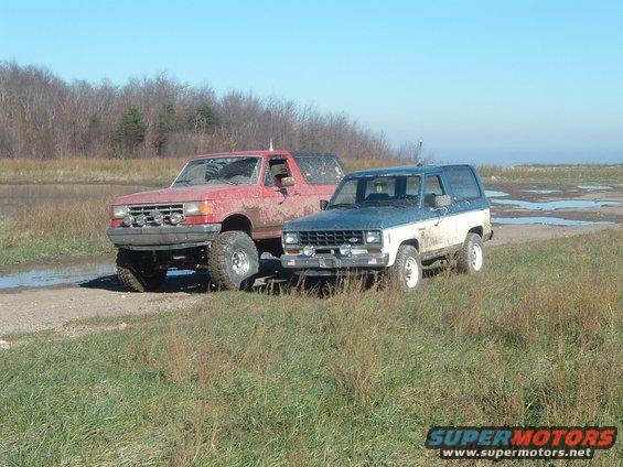 1987 Ford Bronco and another SUV on a dirt road