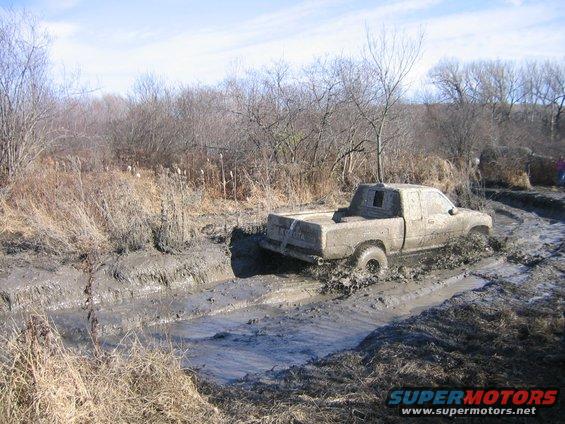 Muddy pickup truck navigating a deep mud pit