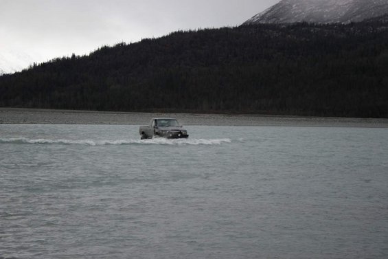 Gray pickup truck driving through shallow water, front view