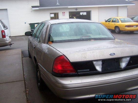 Rear view of a tan 2001 Ford Crown Victoria parked next to a yellow Ford Crown Victoria