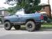 1986 Ford Bronco - Modified blue Ford Bronco parked on a suburban street, showing its lifted suspension and off-road tires.