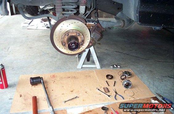 Front brake assembly on jack stand, with tools and parts laid out on cardboard