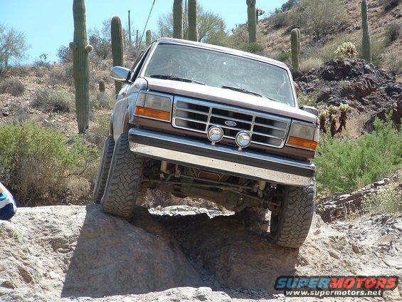 1993 Ford Bronco navigating rocky terrain with saguaro cacti in the background