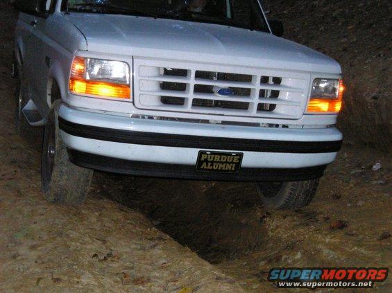 White Ford Bronco with a Purdue Alumni license plate, angled front view, driving on a dirt trail