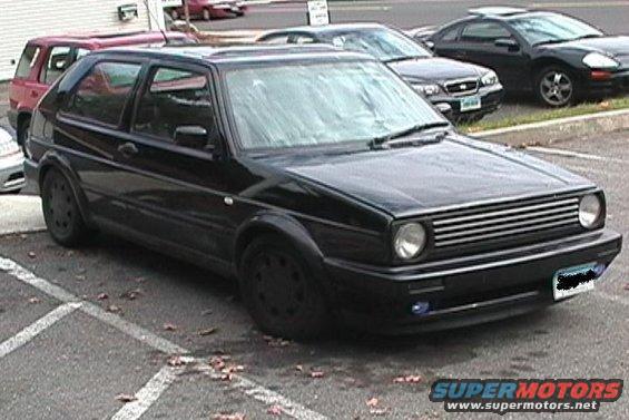 black Volkswagen Golf GTI parked in a lot, other cars visible