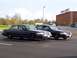 1998 Ford Crown Victoria - Two dark blue 1998 Ford Crown Victoria sedans are parked in a lot near a casino.