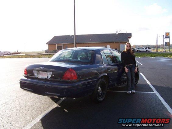 Dark blue 2001 Ford Crown Victoria parked in a lot with a woman leaning on it