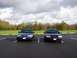 1998 Ford Crown Victoria - Two dark blue Ford Crown Victorias are parked facing forward in a parking lot under a cloudy sky.