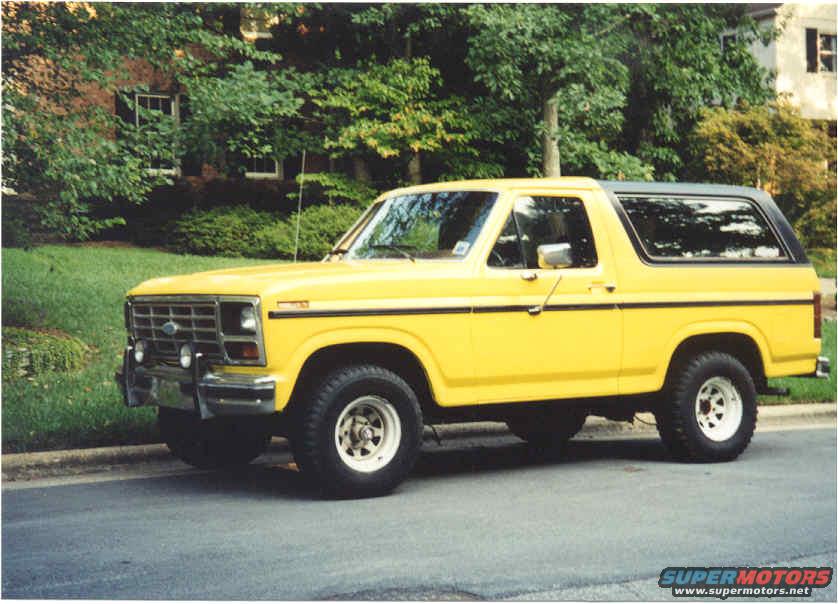 Yellow 1985 Ford Bronco parked curbside, 3/4 front view