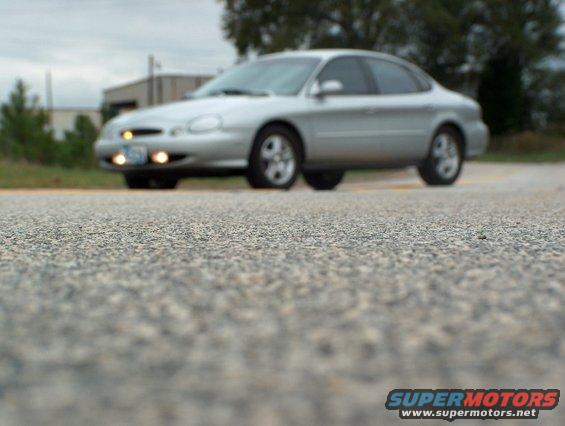 Silver 1998 Ford Taurus sedan, front 3/4 view, driving on a paved road