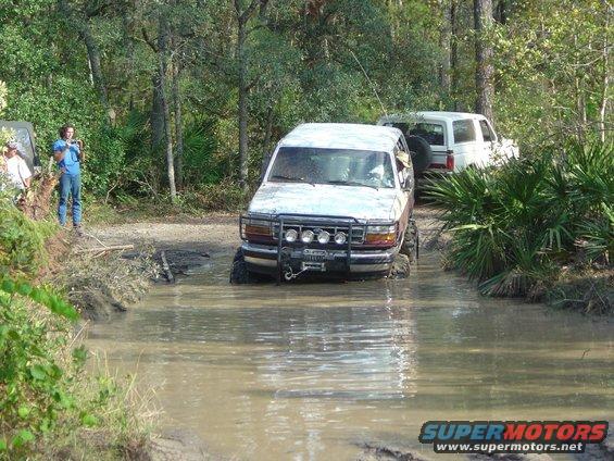 1993 Ford Bronco navigating a muddy trail with another SUV behind it