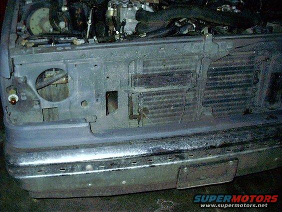Front end of a truck with grille and radiator exposed, bumper visible