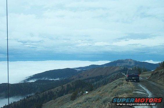 Dark SUV on a dirt road with a cloud inversion below