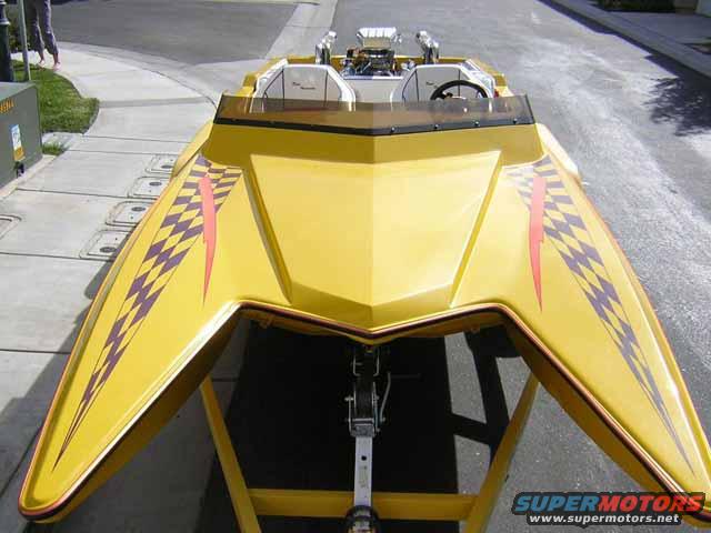 Yellow boat with checkered flag and lightning bolt graphics, on a trailer