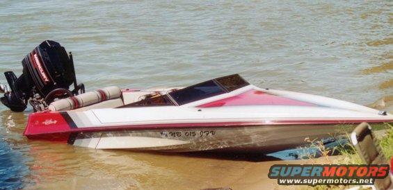 White and red speed boat with a black Mercury outboard motor, partially submerged at the water's edge