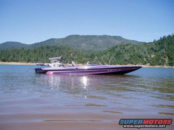 Purple boat on lake with wooded hills in background