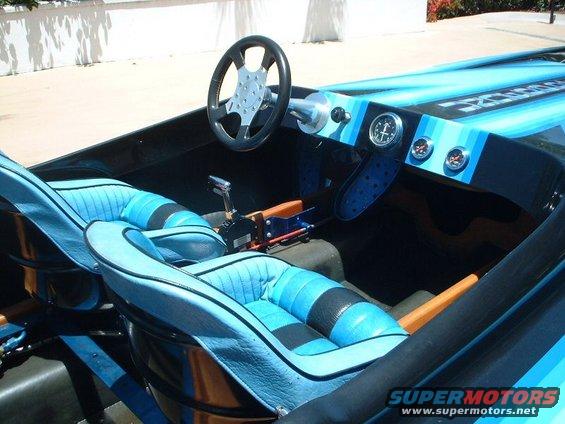 Boat interior with blue striped seats, steering wheel, and gauges