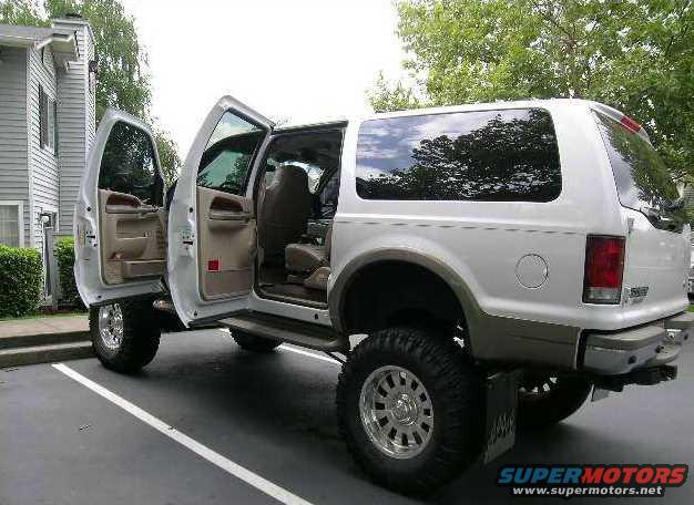 White 2000 Ford Excursion SUV, driver and passenger doors open, parked in a lot