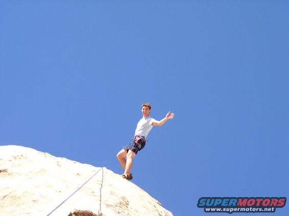 Rock climber on a cliff face against a blue sky