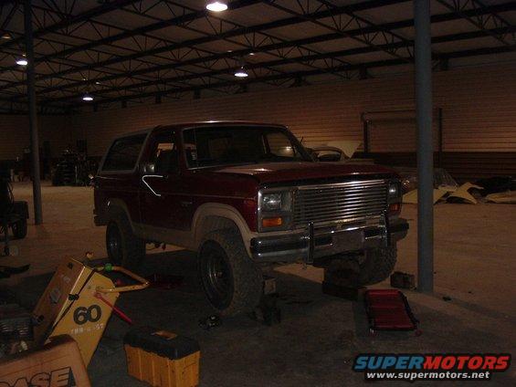 Red Ford Bronco on jack stands in a garage, front end raised
