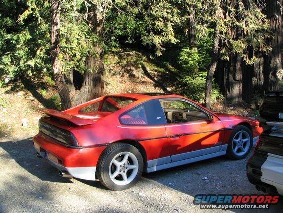 Red 1986 Pontiac Fiero GT parked outdoors with trees in background