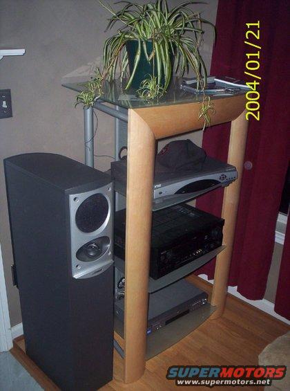 Stereo equipment on a shelf with a plant on top, next to a speaker