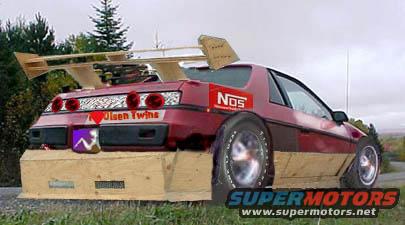 Red 1986 Pontiac Fiero with wooden body kit and large spoiler, rear view